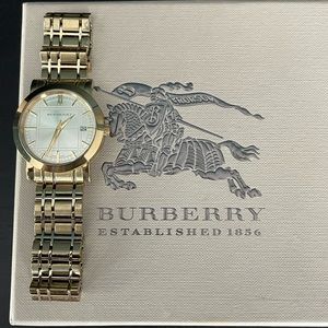 Burberry gold tone watch with iconic plaid details. Round face with date